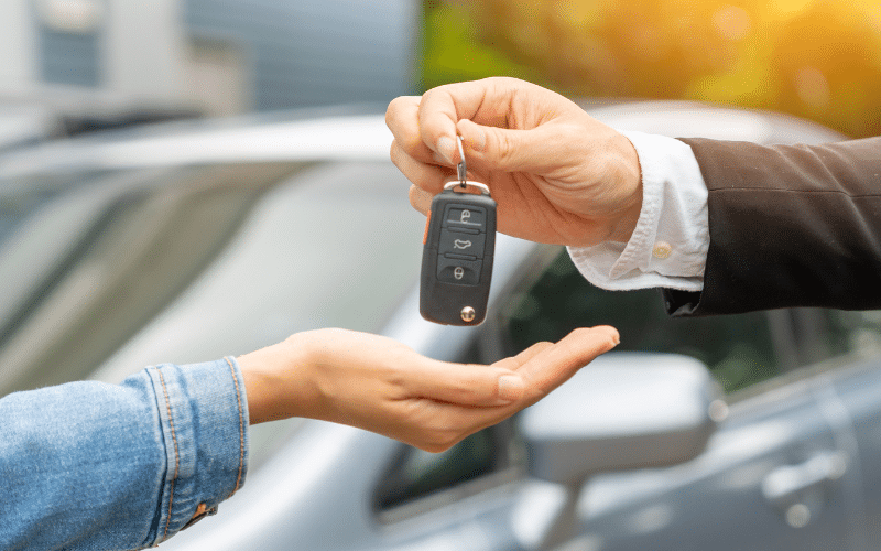 Man handing rental car keys to woman