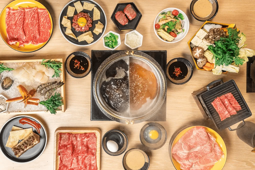 A large selection of side dishes and meat including bone marrow, brisket, a seafood platter, and sauces at Mikiya Wagyu Shabu House in Las Vegas