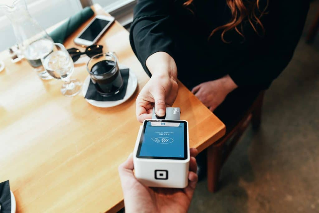 Woman putting visa card into Square POS system