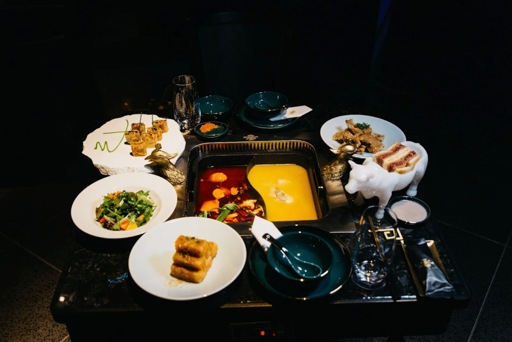 Selection of meats and dishes surrounding a pot with two broths at The X Pot in The Venetian Las Vegas