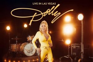 Dolly Parton holding a guitar promoting Vegas show at Caesars Palace.