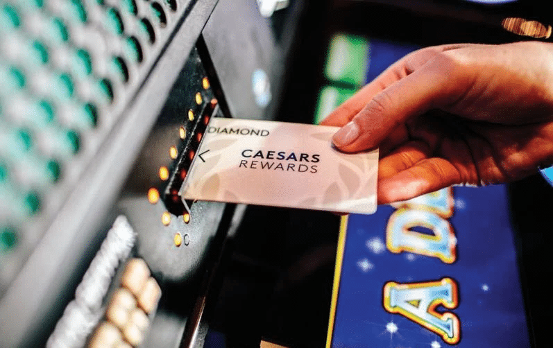 Someone putting Diamond Caesars Rewards card in a slot machine at a Caesar Resort property