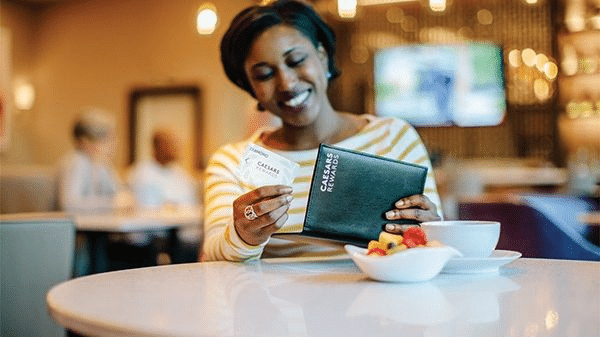 Woman using Caesar Reward points to redeem dining credits 